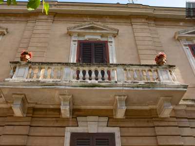 Il piano superiore invece, riproponendo lo schema tripartito di quello inferiore, presenta delle lesene che scandiscono i tre spazi occupati dai finestroni. Al centro quattro mensoloni sorreggono un ampio balcone in pietra, abbellito da un elegante balaustra e una coppia di vasi floreali. Chiude la facciata un cornicione marcapiano che corre lungo tutto il perimetro dello stabile

